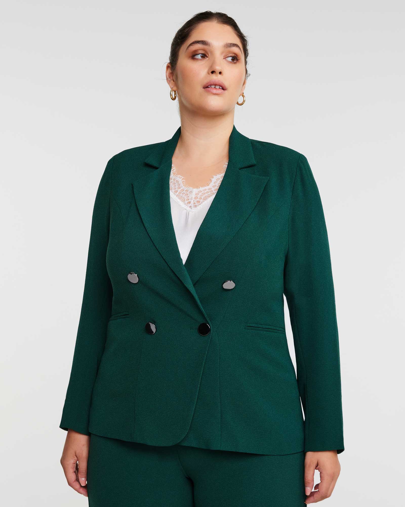 A woman wearing the Estelle Clever Blazer Jacket in Green and pants.