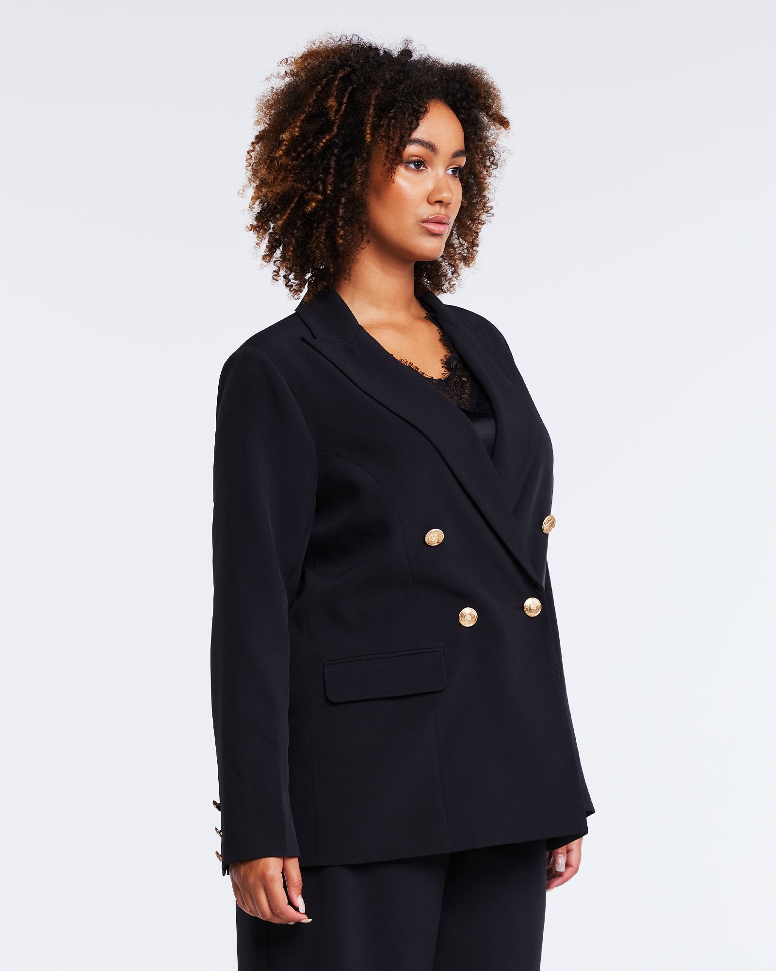 The model is wearing a plus-size Savannah Double-Breasted Black Blazer with gold buttons.