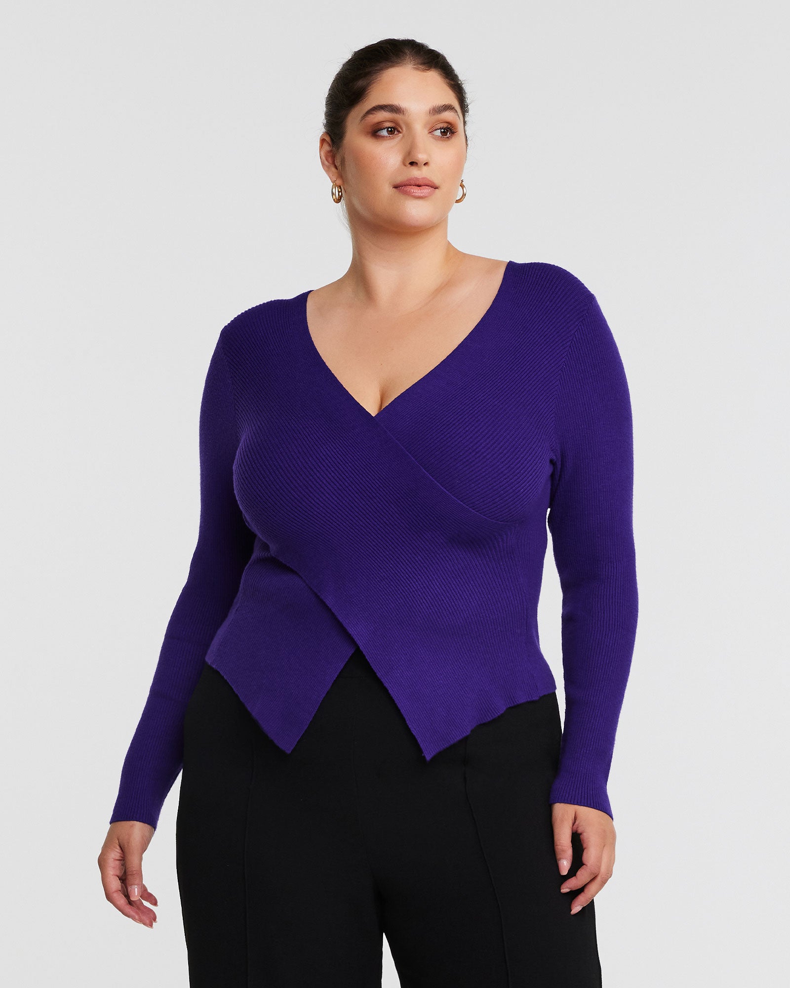 A woman wearing Estelle's Purple Wrap It Up Long Sleeve Knit Sweater and black pants.