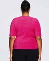 The back view of a plus-size woman wearing a Nora Fuzzy Pink Short Sleeved Sweater.