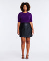 A woman wearing a purple sweater and Estelle Lucinda Black Pleather Mini Skirt.