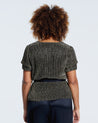 The back view of a woman wearing an Estelle Vega Tie Top and black pants.