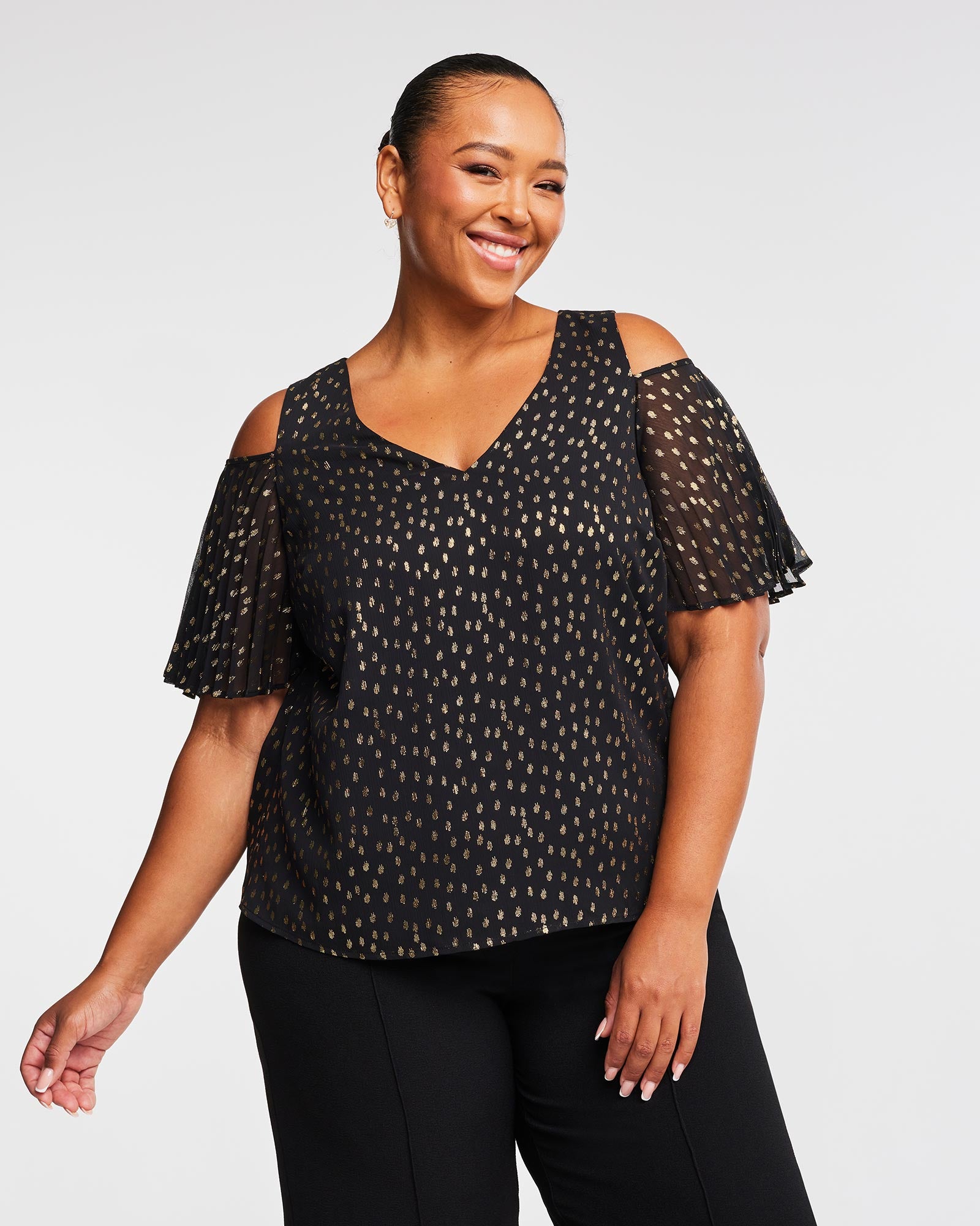 A plus size woman wearing an Estelle Gold Dust Cold Shoulder Top.