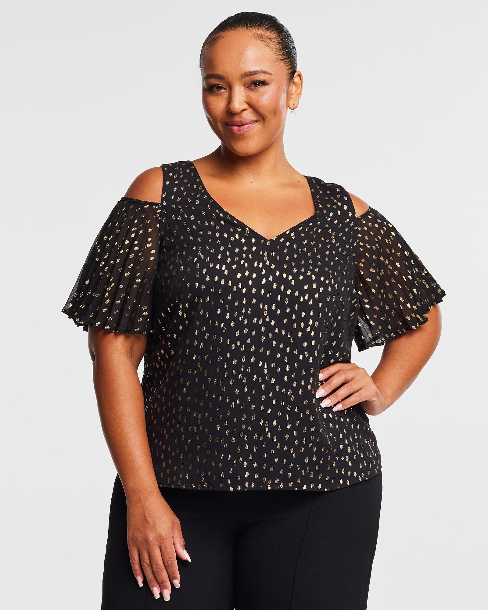 A plus size woman wearing the Estelle Gold Dust Cold Shoulder Top.